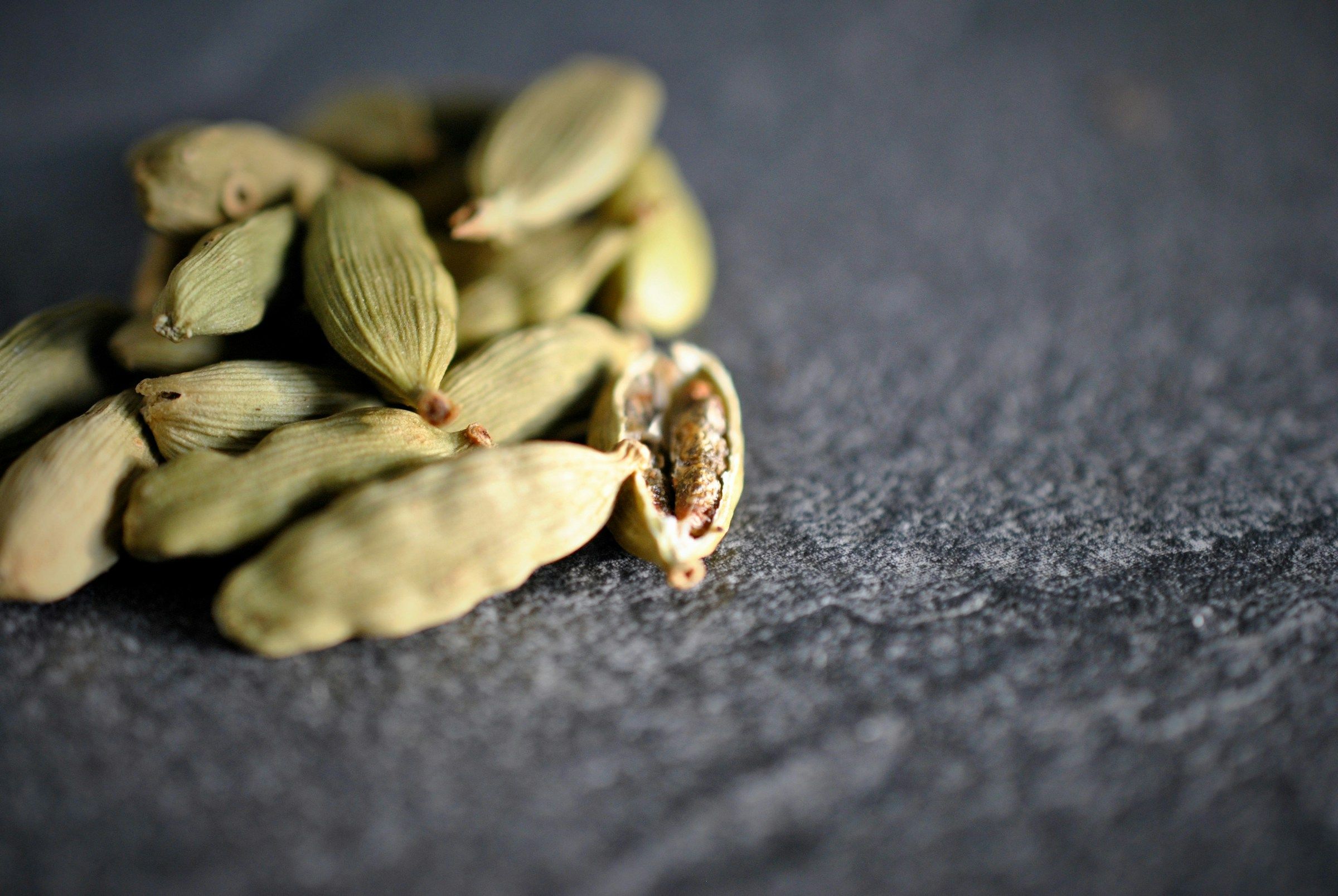 Bold green cardamom pods on a dark surface