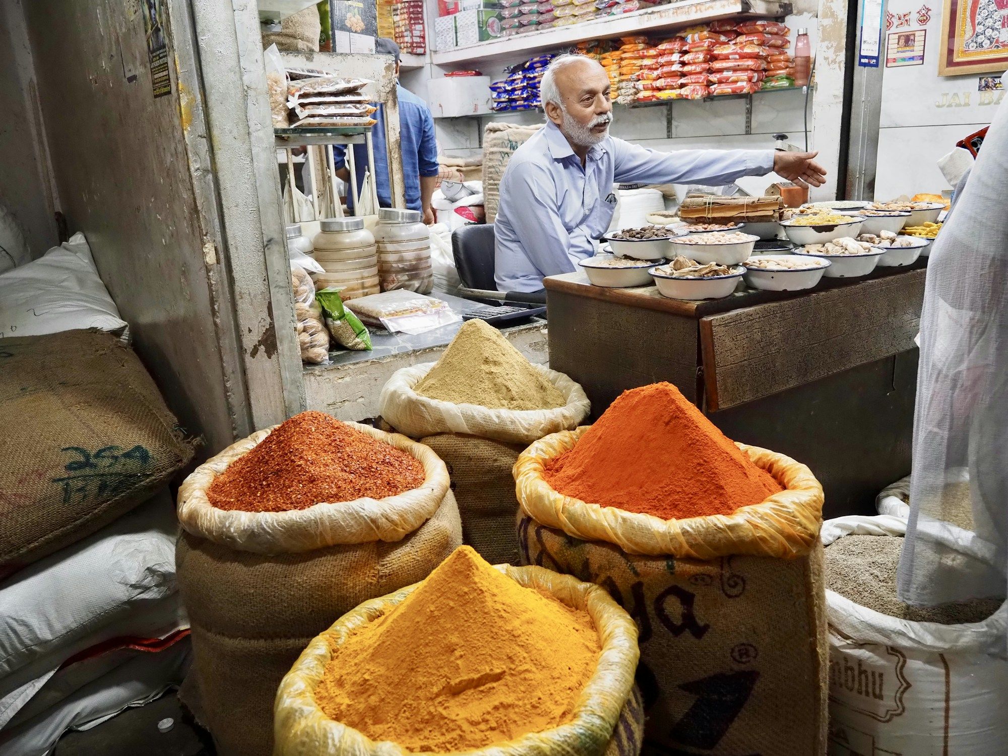 A spice trader weighing whole spices from open sacks at a wholesale market