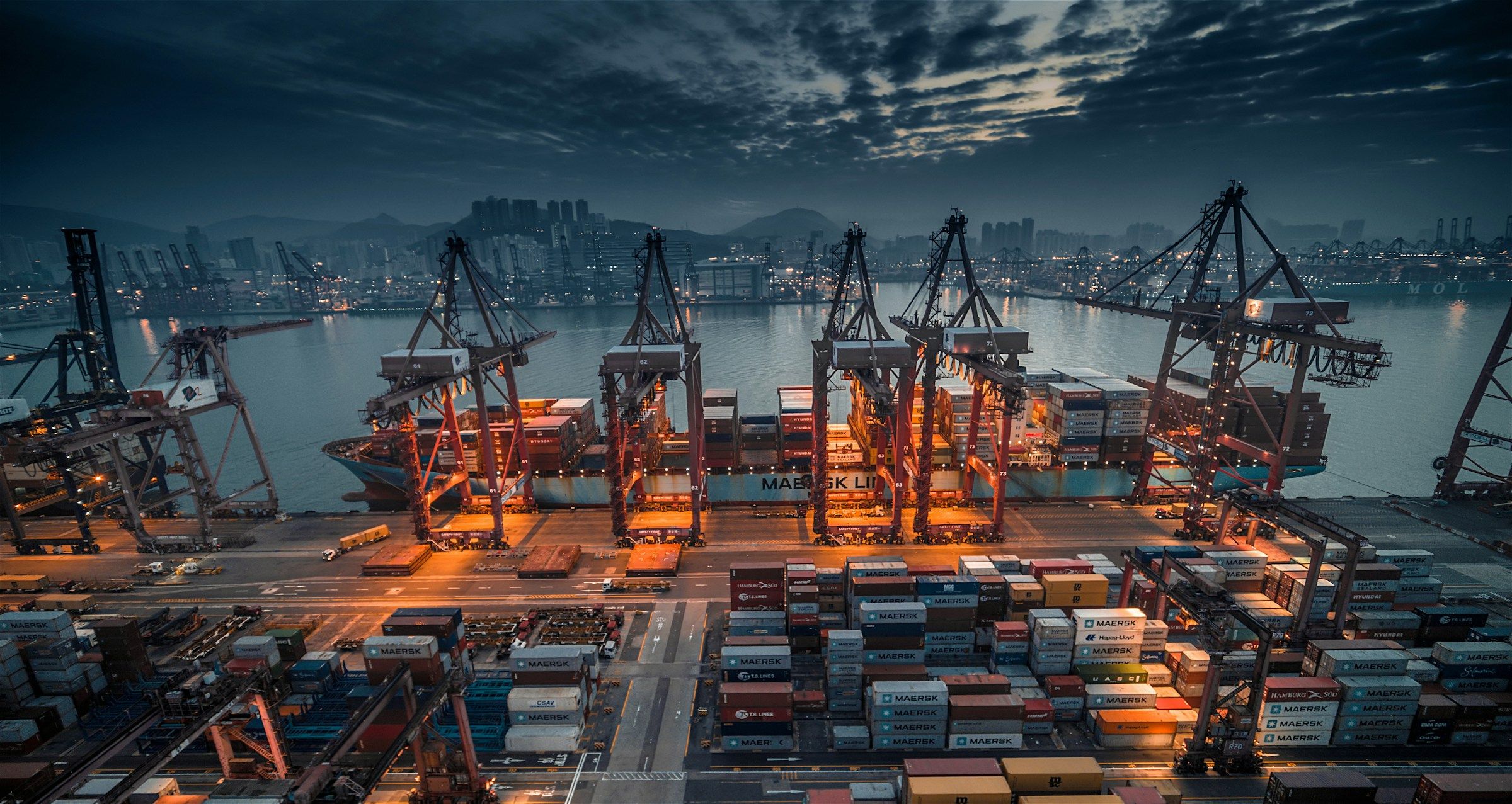 Container ship being loaded by cranes at dusk